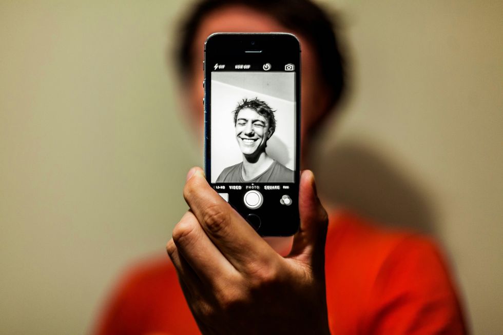 ​Person holding an iPhone to take a photo of themself, Dec. 29, 2017.