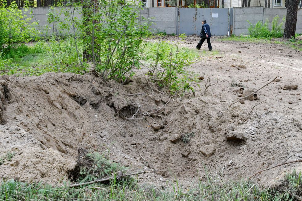 ​Photo of a Ukrainian civilian walking by a shelling crater in Sviatohirsk.