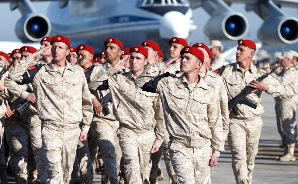 ​photo of Russian soldiers parade past the review stand during the arrival ceremony for Russian President Vladimir Putin at Khmeimim Air Base Dec. 11, 2017 in Latakia, Syria.