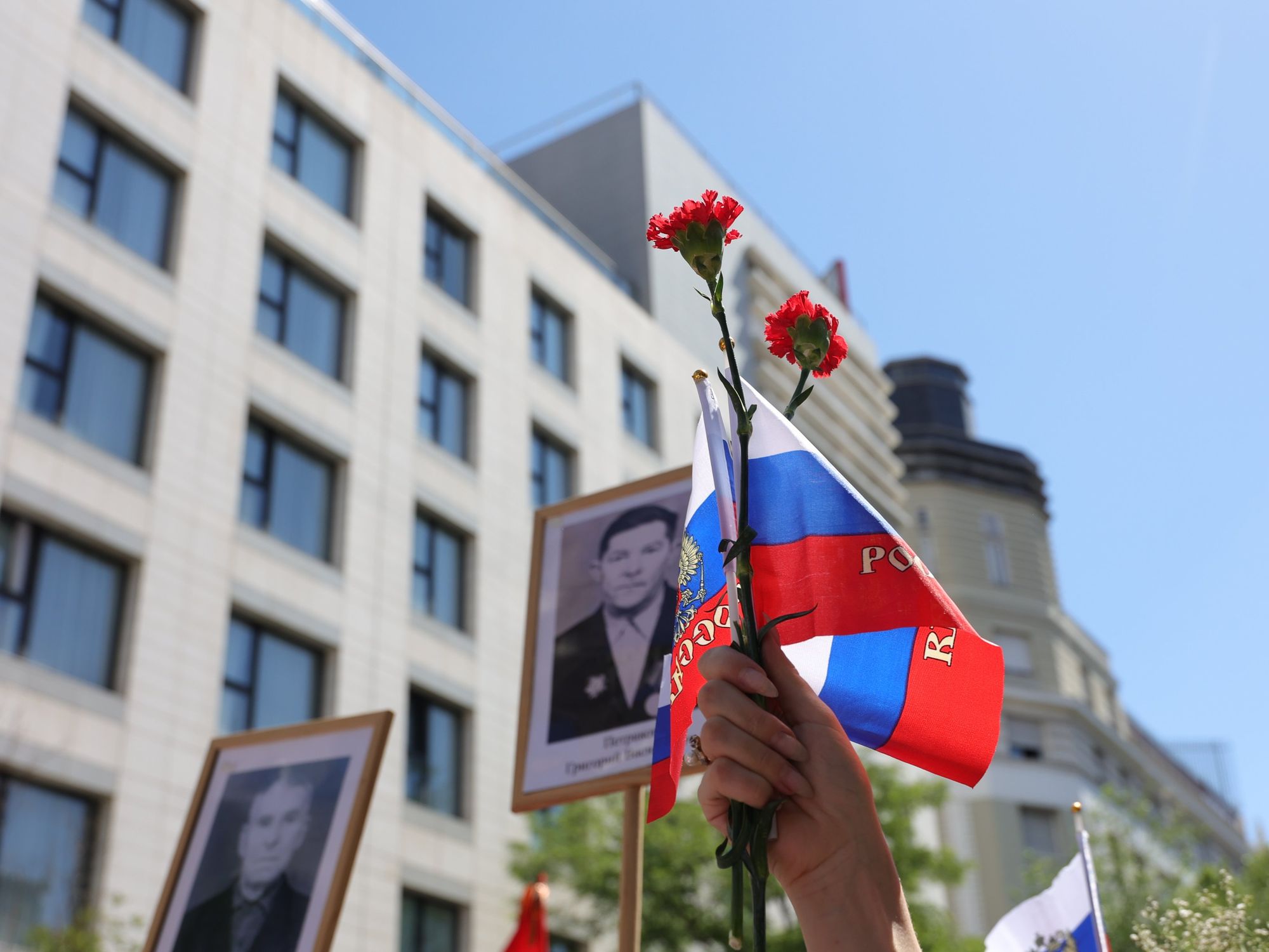 ​Russian flag and roses being held in the air.