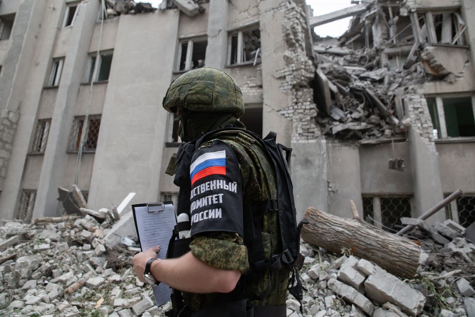 ​Soldier in front of damages from military strikes on Stakhanov, Lugansk People's Republic