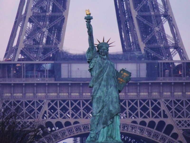 ​Statue of liberty in France stands in front of the Effiel Tower.