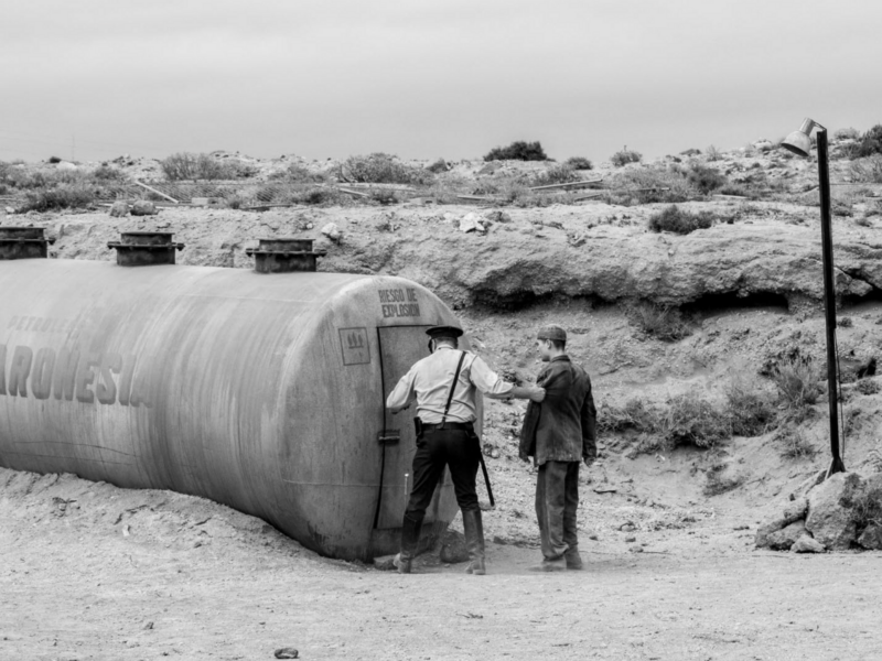 ​Still image from the black-and-white 2023 TV series "Las Noches de Tefía" showing a prisoner being led by a guard at the Tefía camp