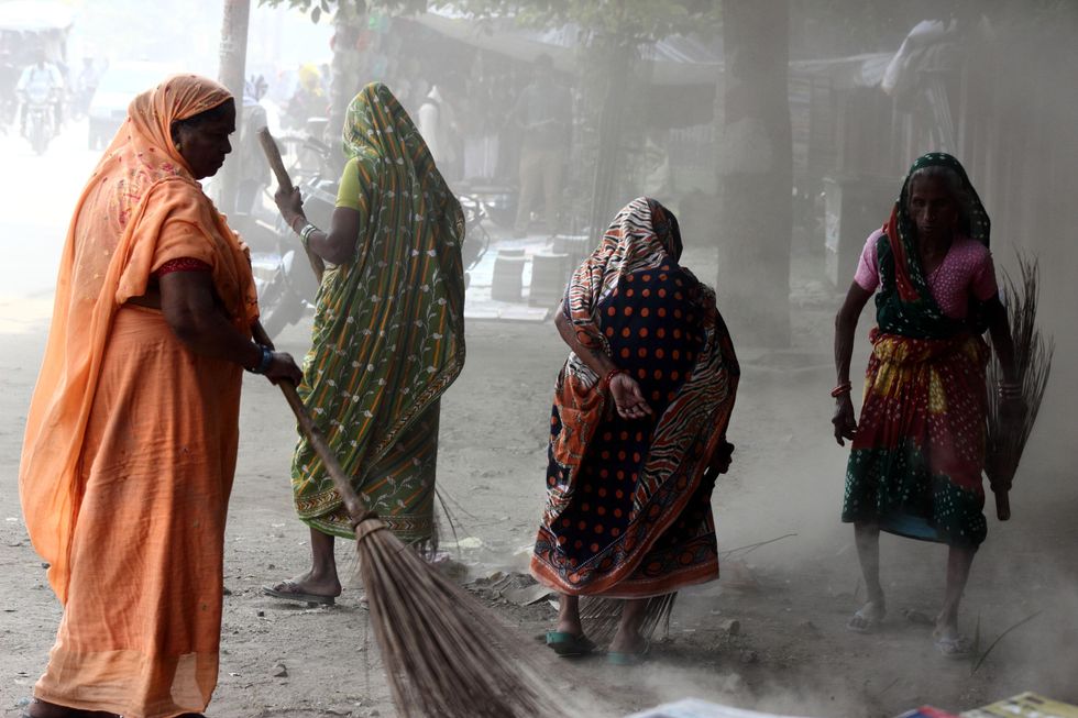 Sweepers surrounded by dust cleaning the streets of Allahabad, India