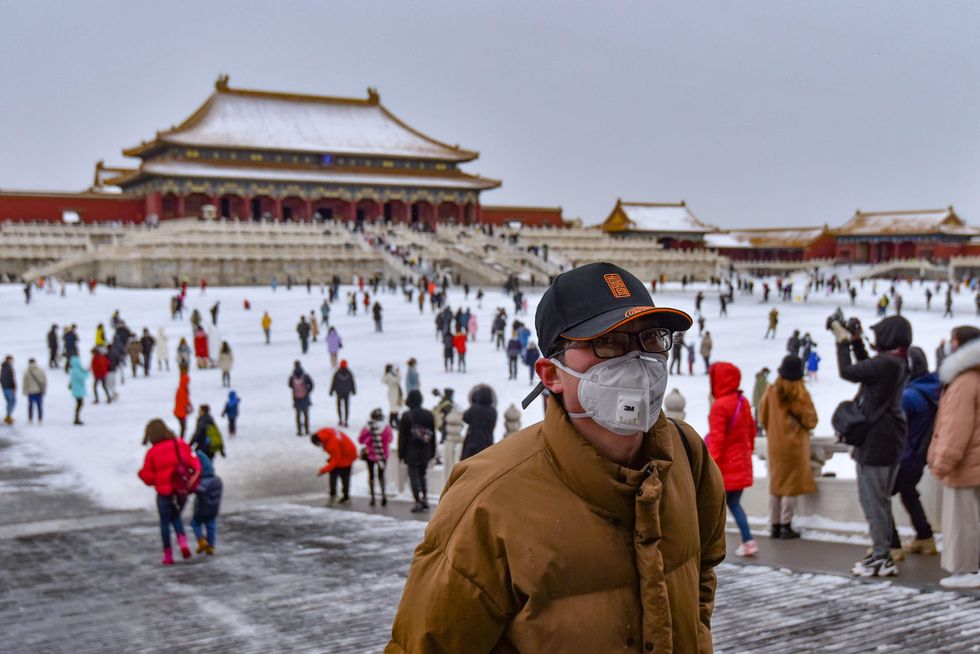 ​Tourists wearing face masks visit the Forbidden City in Beijing after a snowfall