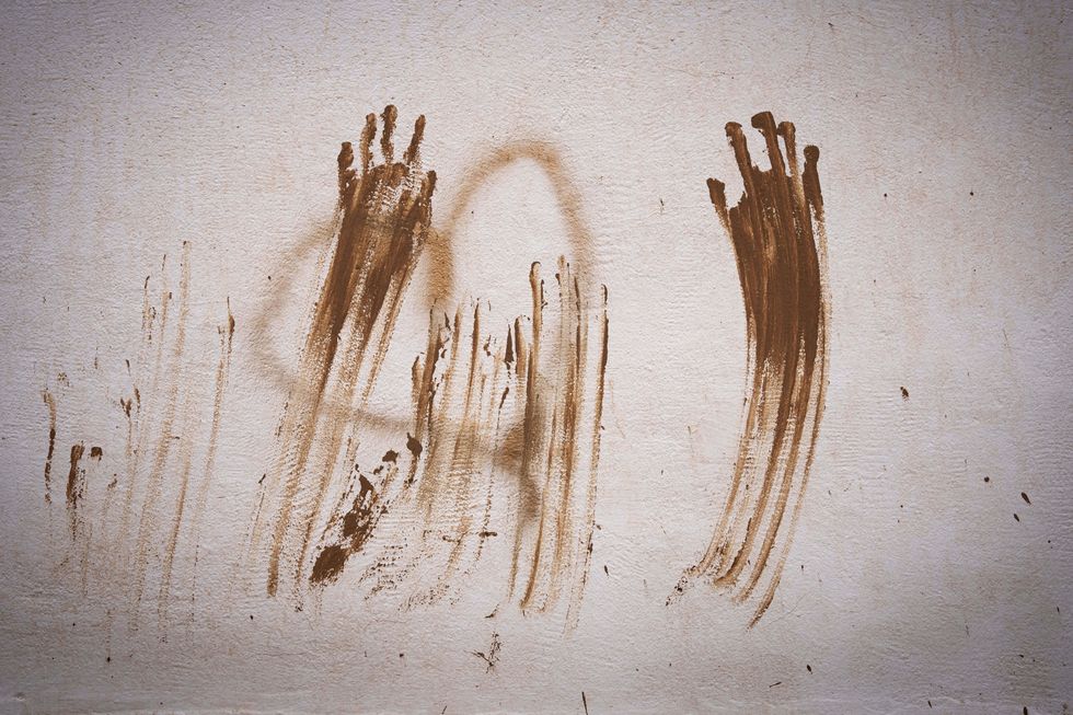 ​Two hands on a wall of a house in Aldaia, Spain leave mud marks after flash floods.