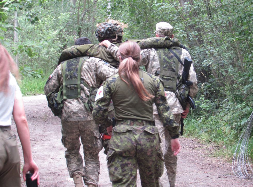 ​Ukrainian soldiers help one of their own walk in Poland.