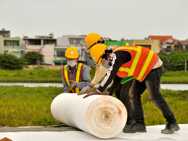 ​Vietnamese construction workers apply plastic sheeting during cleanup work of contaminated land