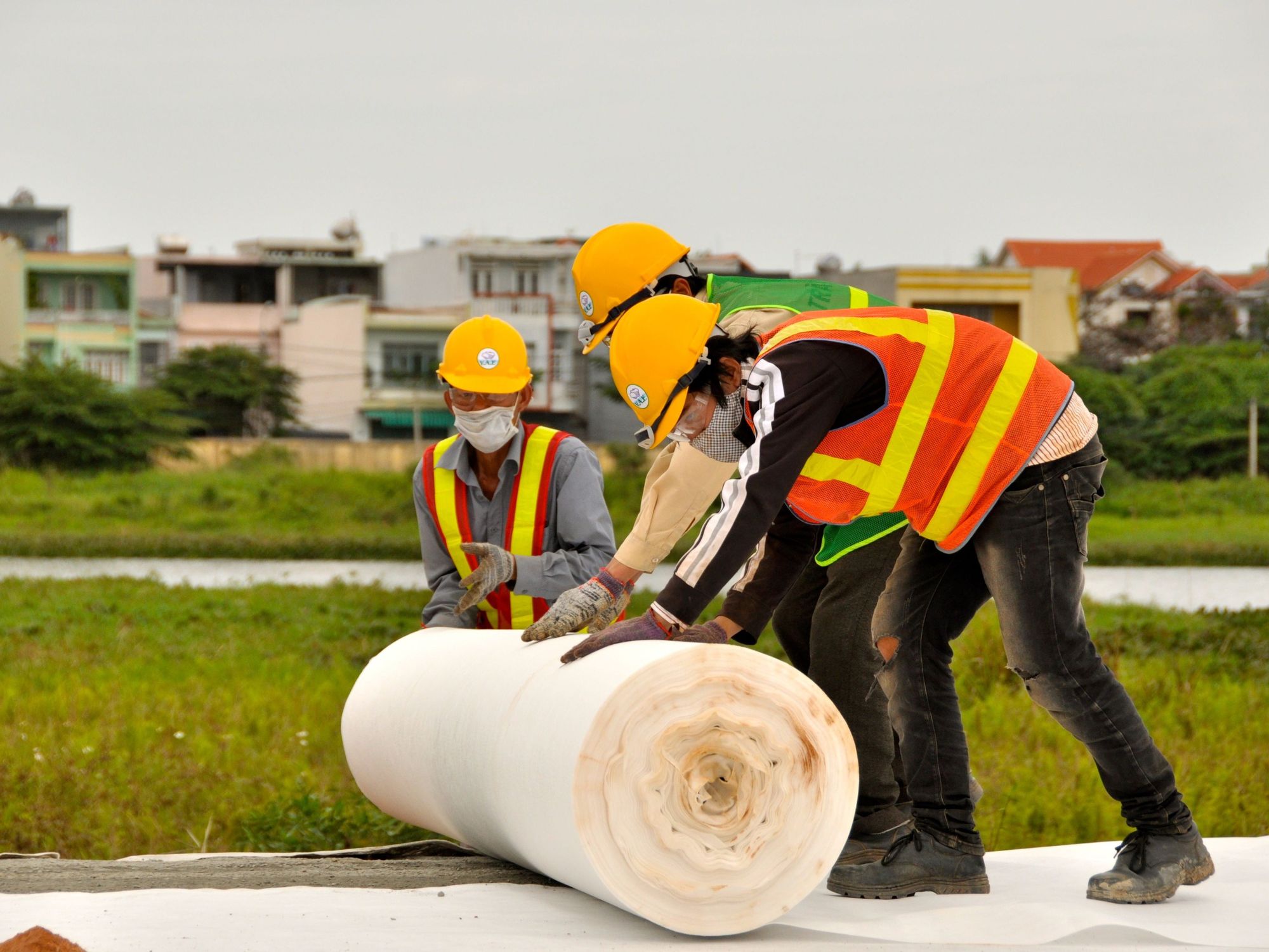 ​Vietnamese construction workers apply plastic sheeting during cleanup work of contaminated land