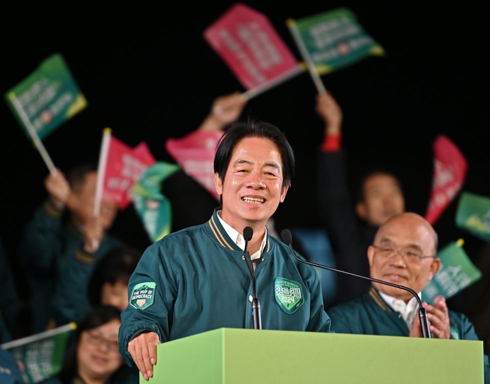 ​William Lai giving a speech with flags being flown behind him.