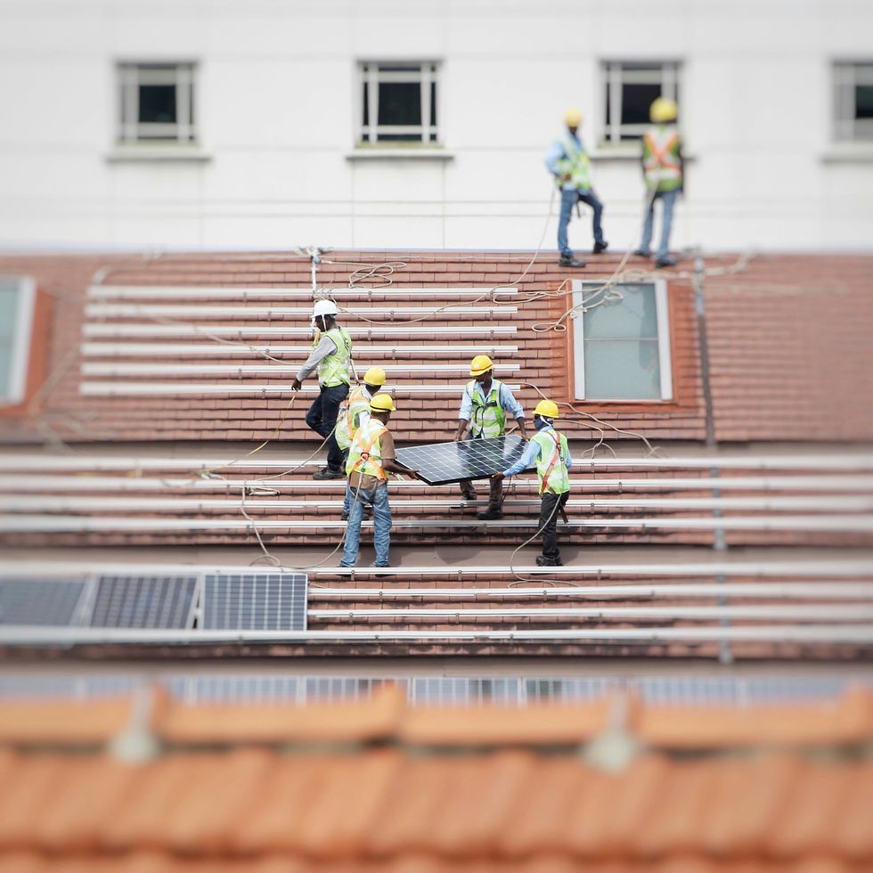 ​Workers installing solar panels on a roof