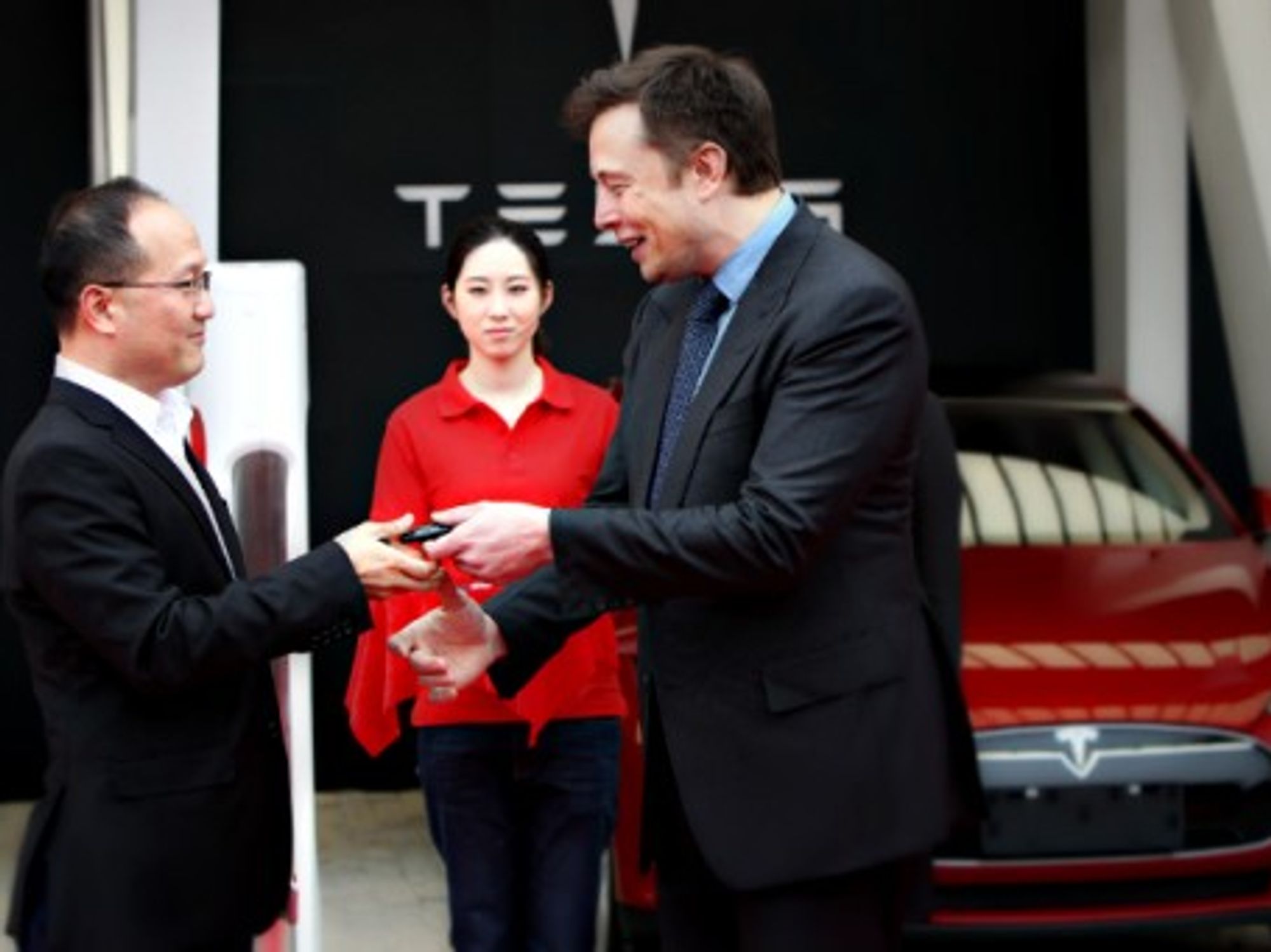 Elon Musk (right) hands the key of a Tesla car to a customer in Shanghai on April 23, 2014