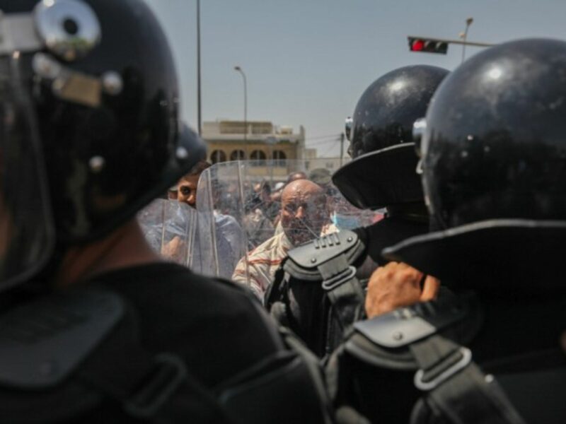Ennahdha supporters facing the riot police during a protest in Tunis on July 26