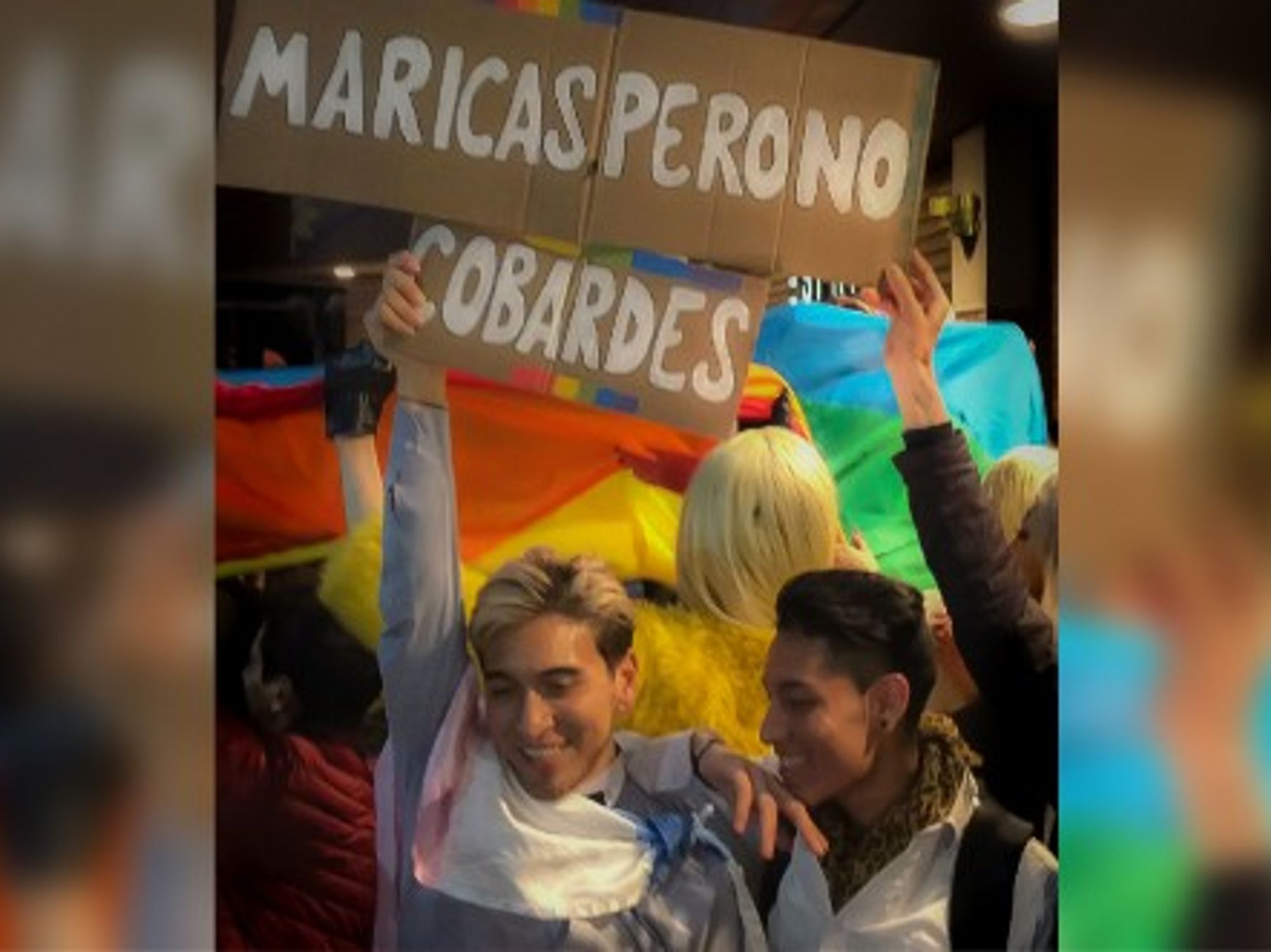 Esteban and Sebastián at the Kiss-a-Thon with a sign saying 'Faggots, but not cowards.' 