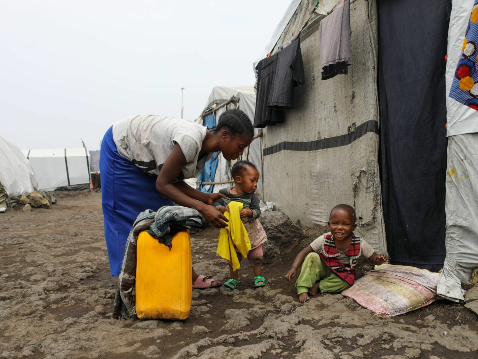 Esther Mwema plays with her two children, Dina Asifiwe, left, and Madina Tumusifu, outside their tent at a camp for displaced people in Munigi. Mwema says Madina, 4, was once treated for mpox, but now she closely guards her children to ensure their health.