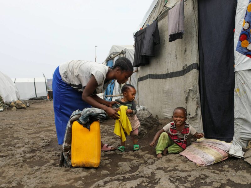 Esther Mwema plays with her two children, Dina Asifiwe, left, and Madina Tumusifu, outside their tent at a camp for displaced people in Munigi. Mwema says Madina, 4, was once treated for mpox, but now she closely guards her children to ensure their health.