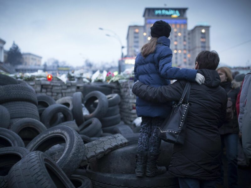 File photo of a mother carrying her daughter on a barricade made of tires in Kyiv