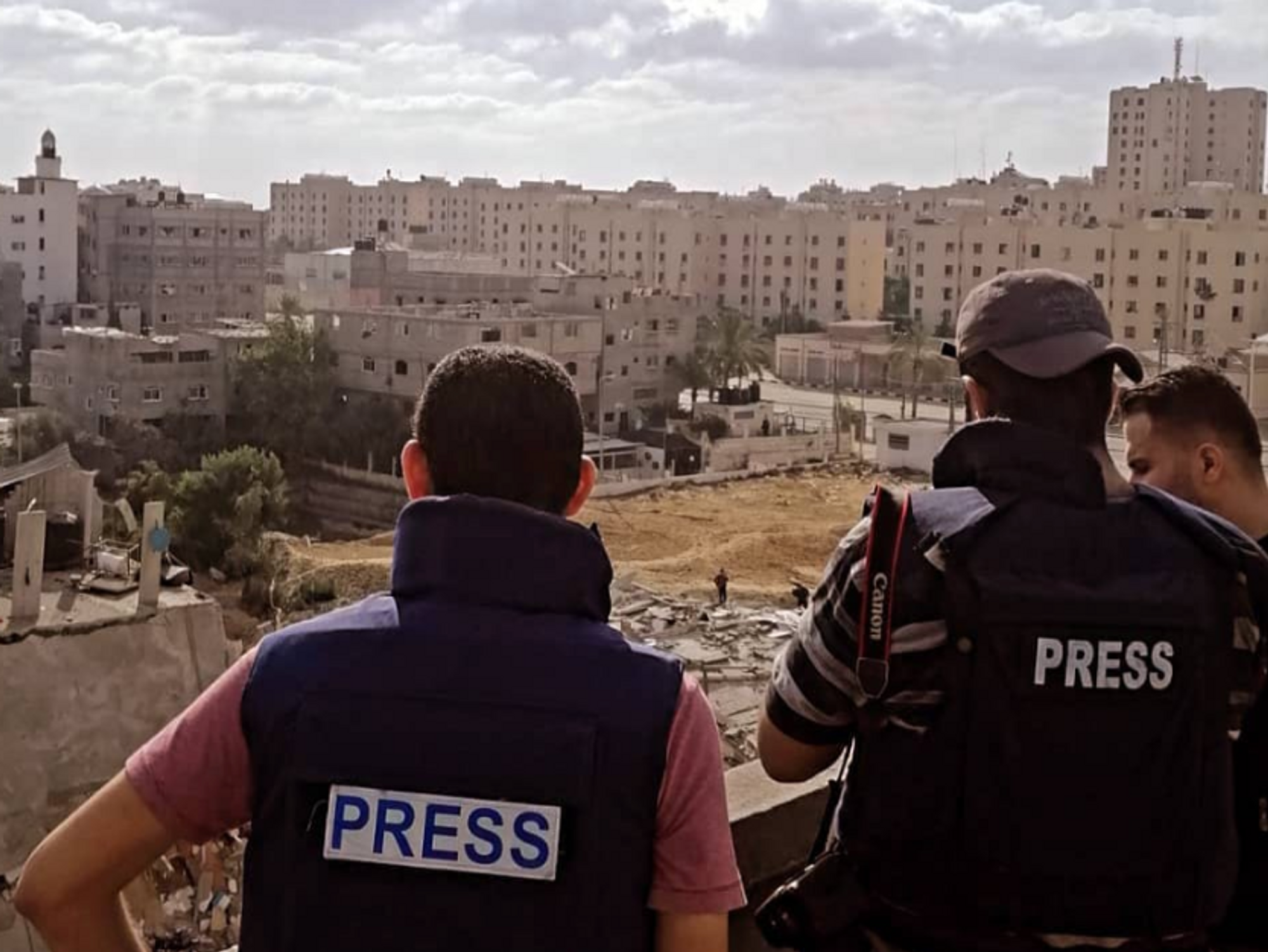 File photo of reporters overlooking destroyed buildings in Gaza