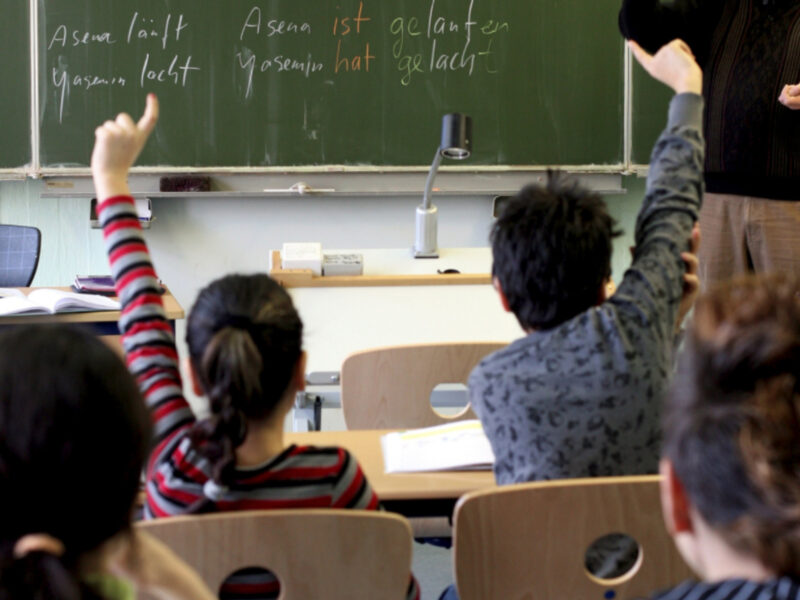 File photo of two students raising their hands in a classroom in Germany