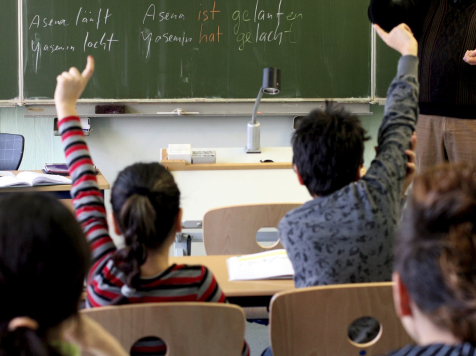 File photo of two students raising their hands in a classroom in Germany