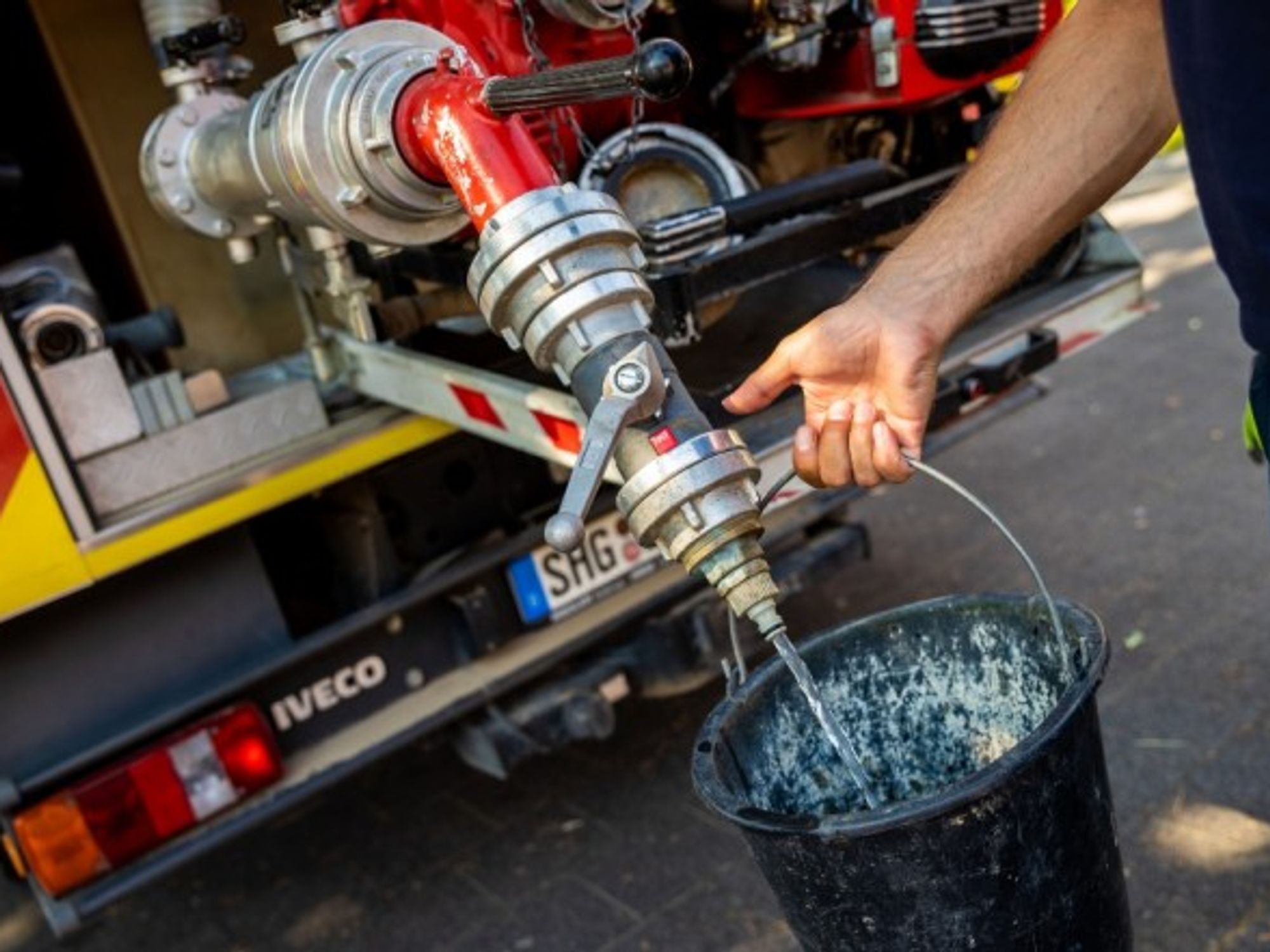 Firefighters of the Lauenau Volunteer Fire Brigade in Germany tapping fire water from the tank of one of their emergency vehicles.