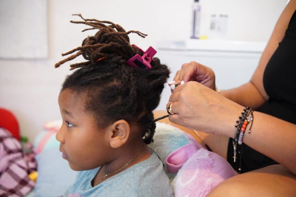 Flor-Angel Guilbe Stevens styles daughter Perla del Mar’s hair at home.