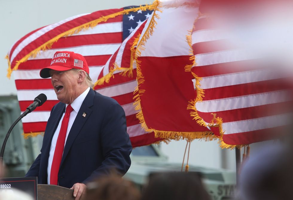 Former President Donald Trump talks at a podium with American flags waving behind him