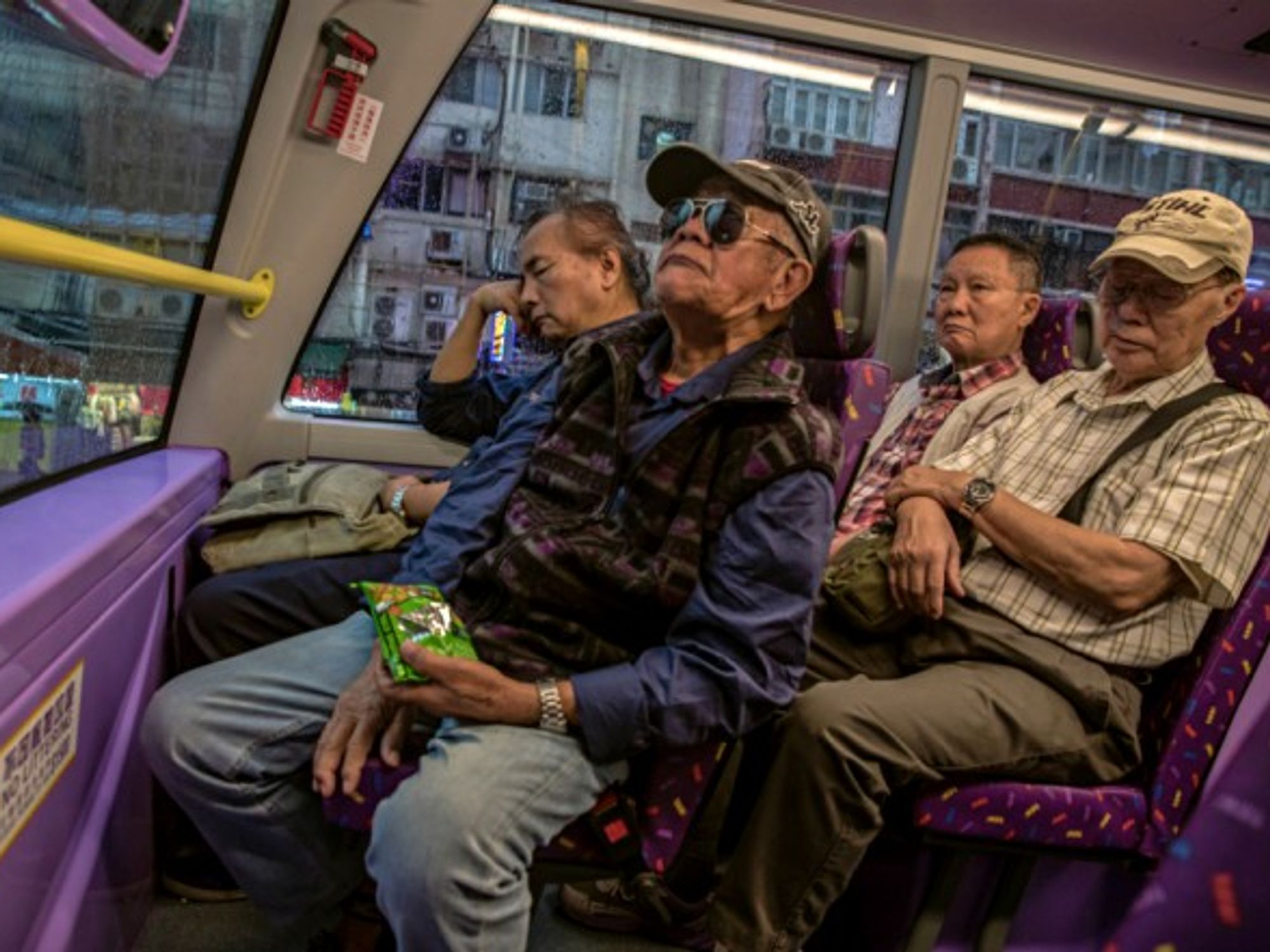 Four elderly men ride the bus home from their day jobs in Hong Kong