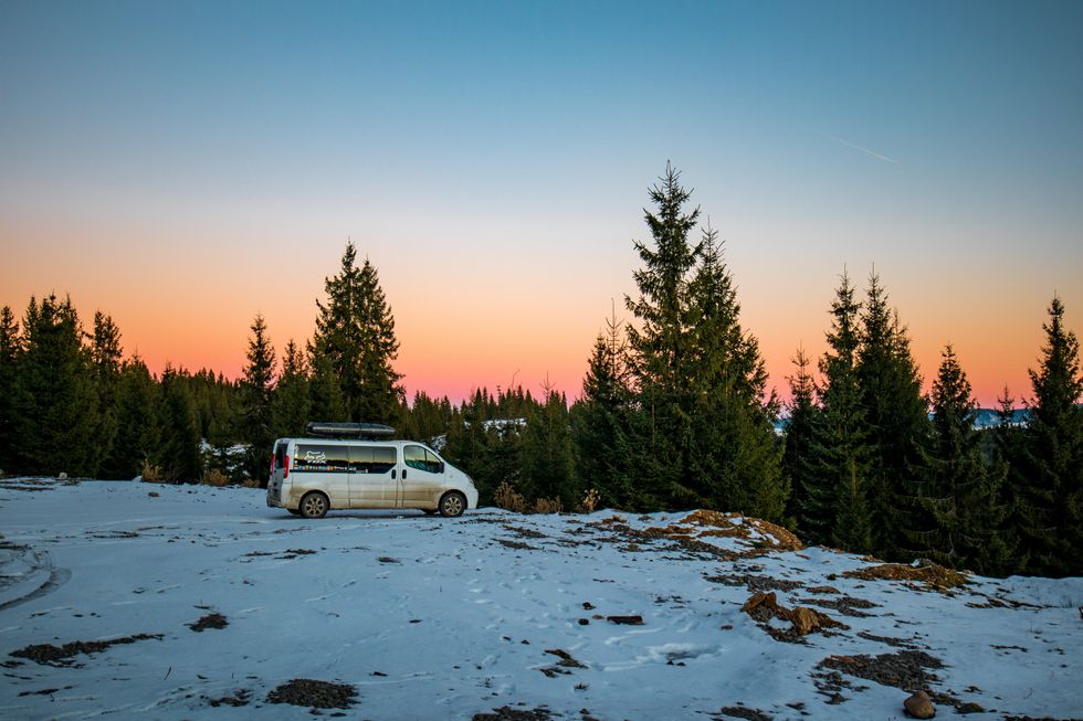 Foxy the van parked on a snowy bank infront of trees and a sunset