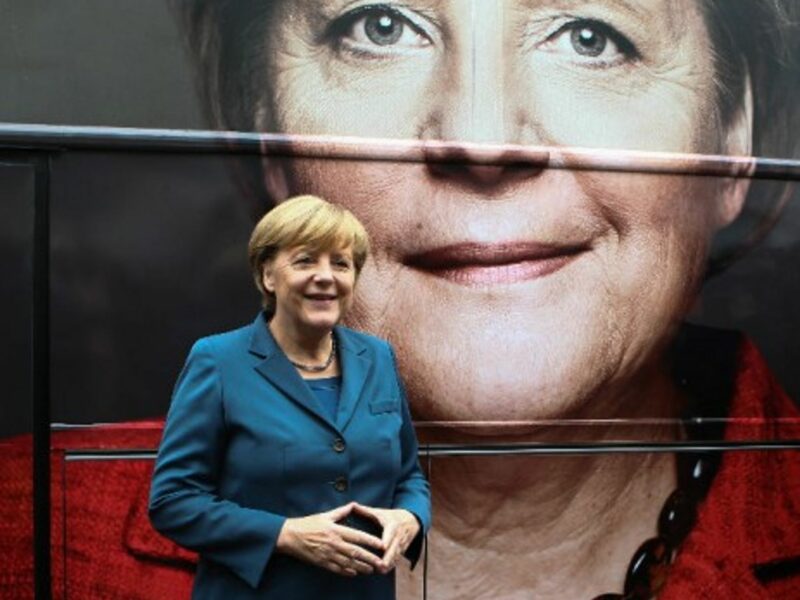 German Chancellor Angela Merkel poses in front of her picture on an campaign bus in Berlin, Germany, on Sept. 16, 2013
