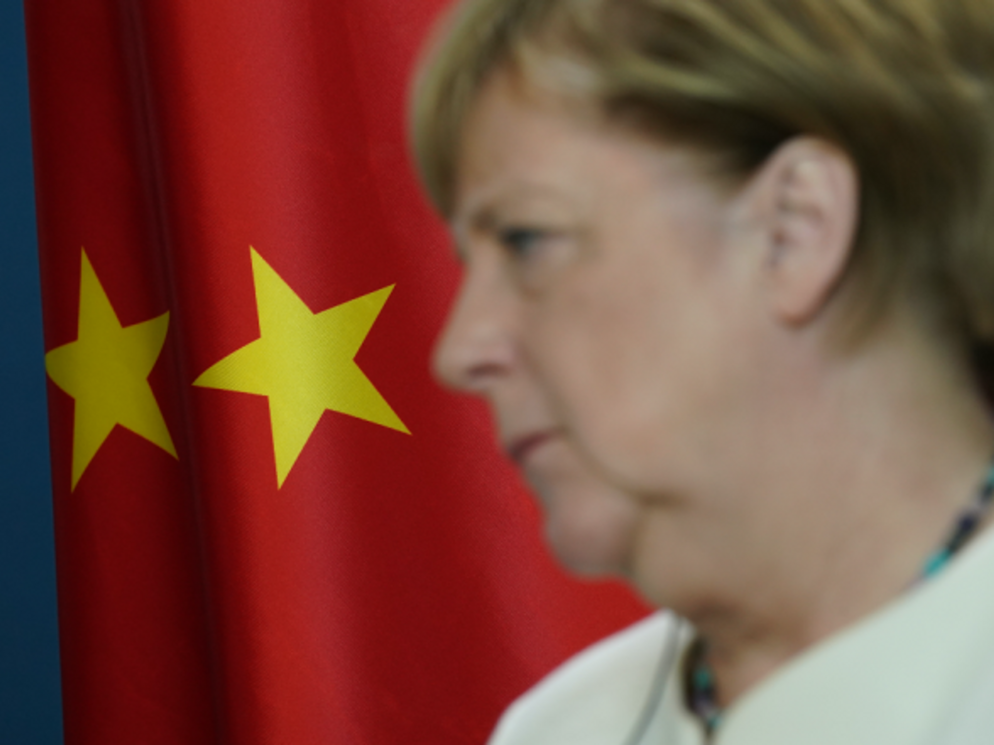 German Chancellor Angela Merkel standing in front of a Chinese flag