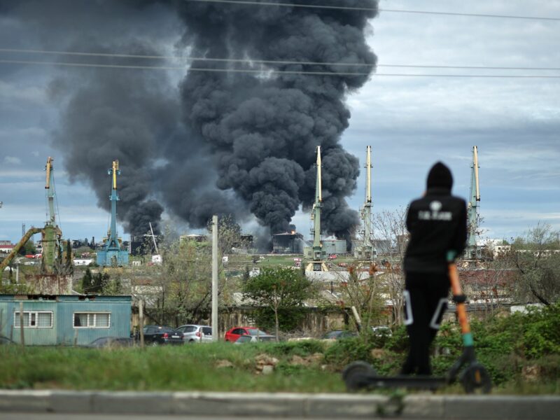 Grey smoke rises out of an oil refinery in a residential neighborhood