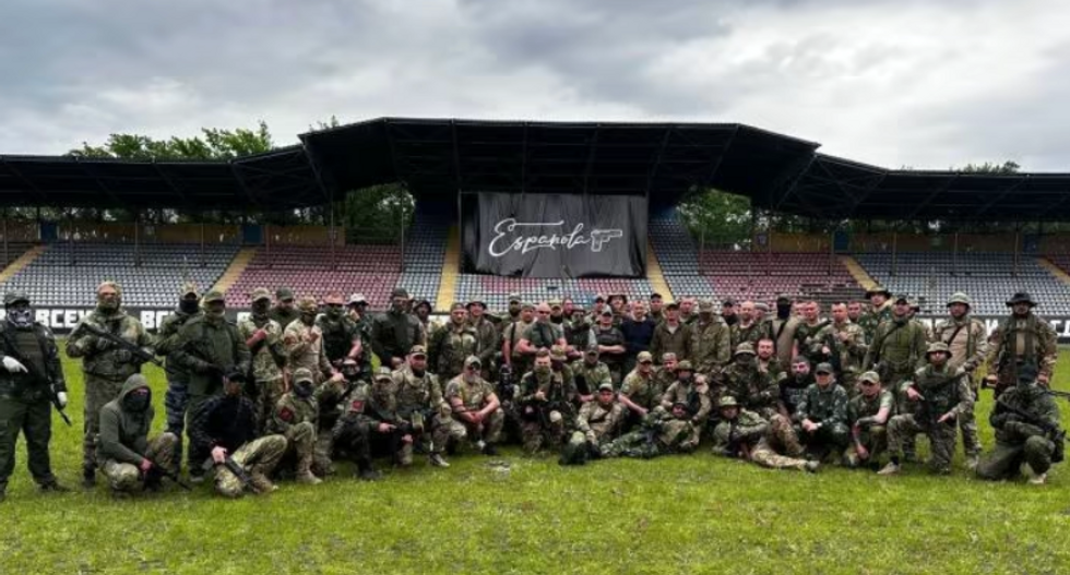 Group photo of PMC Española soldiers posing on a soccer pitch