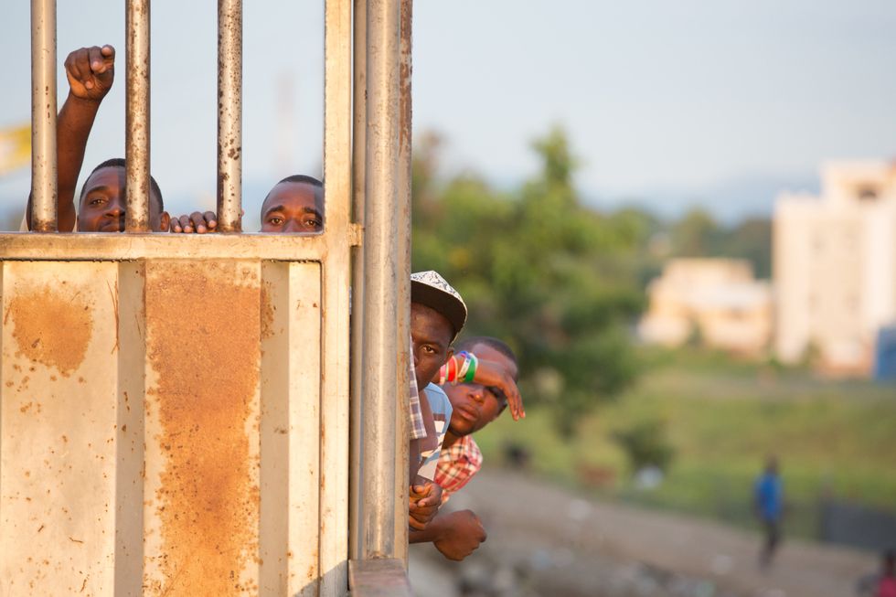 Haitians wait at sunrise to cross the unopened gate on the bridge at the Dominican Republic border in Dajabon.