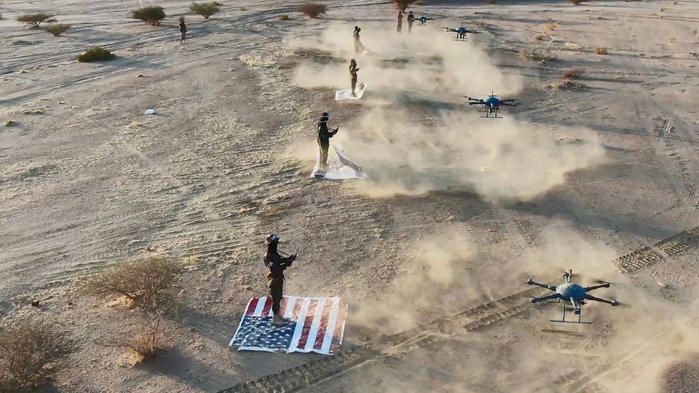 Houthi troopers standing on US and Israeli flags while operating drones during a military exercise near the Yemen-Saudi Arabia border at Al-Baqaa area in the northern province of Saada, Yemen