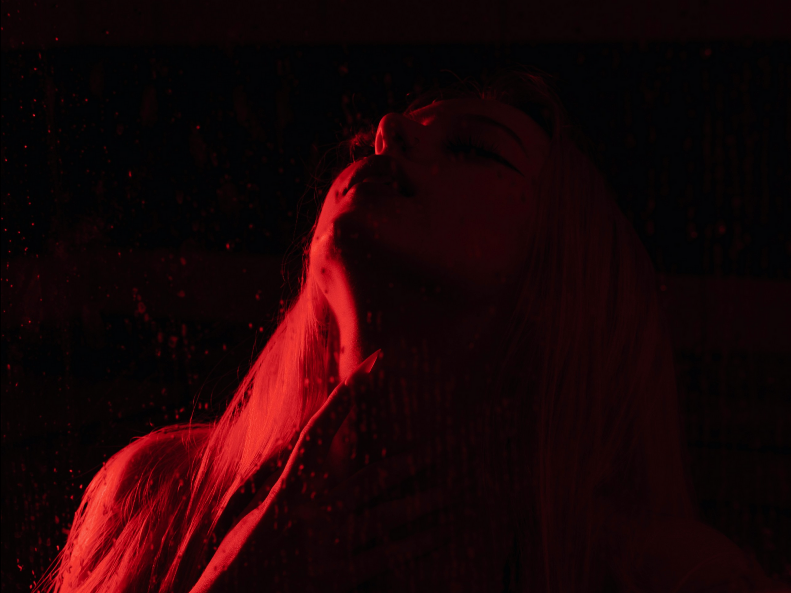 Illustrative photo of a blonde model lit in red light in a dark room