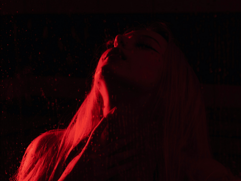 Illustrative photo of a blonde model lit in red light in a dark room