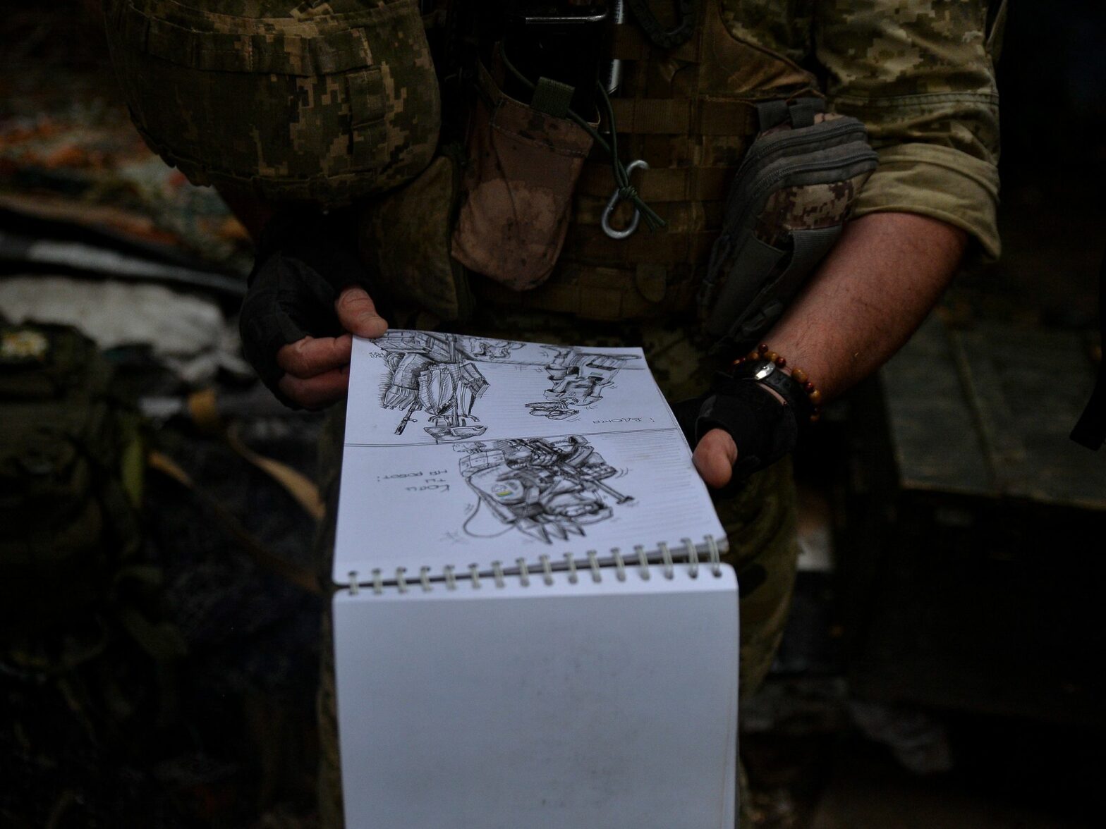 Image depicting a Ukrainian soldier displaying his artistic drawings depicting life in the Ukrainian military during the war