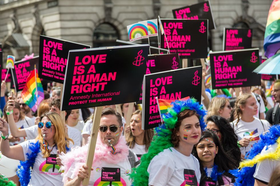 Image ​of people gathering during a protest defending human rights, holding a sign that reads "Love is a human right".