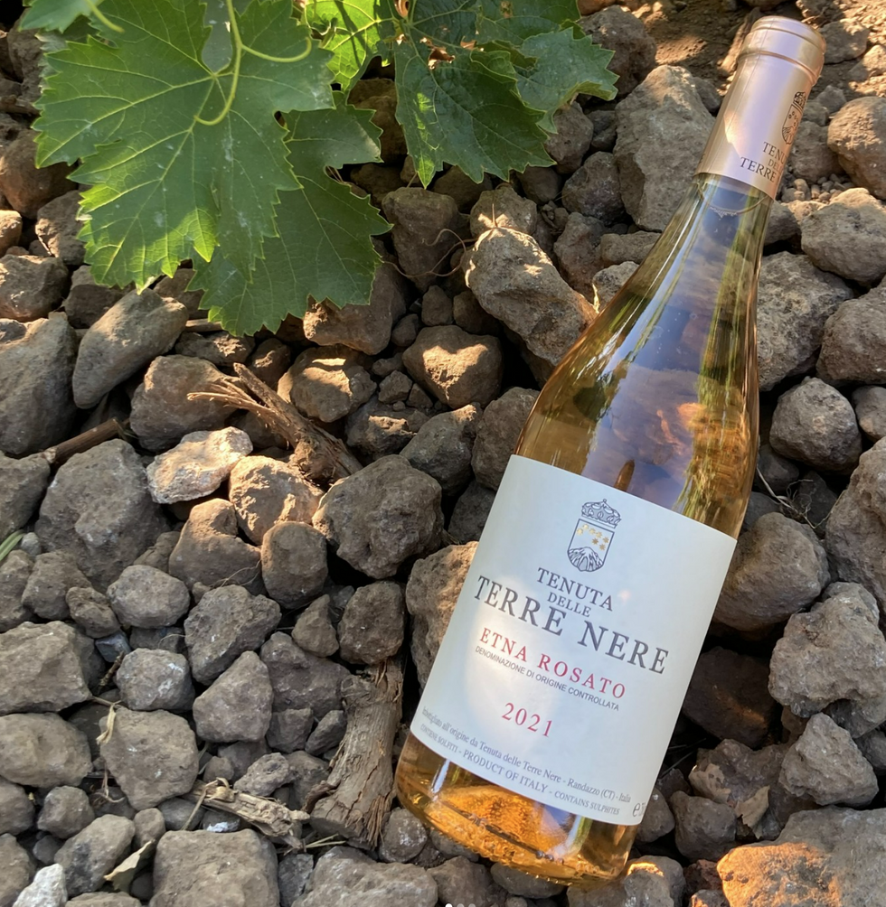 Image of a bottle of Etna Rosato on top of volcanic soil.