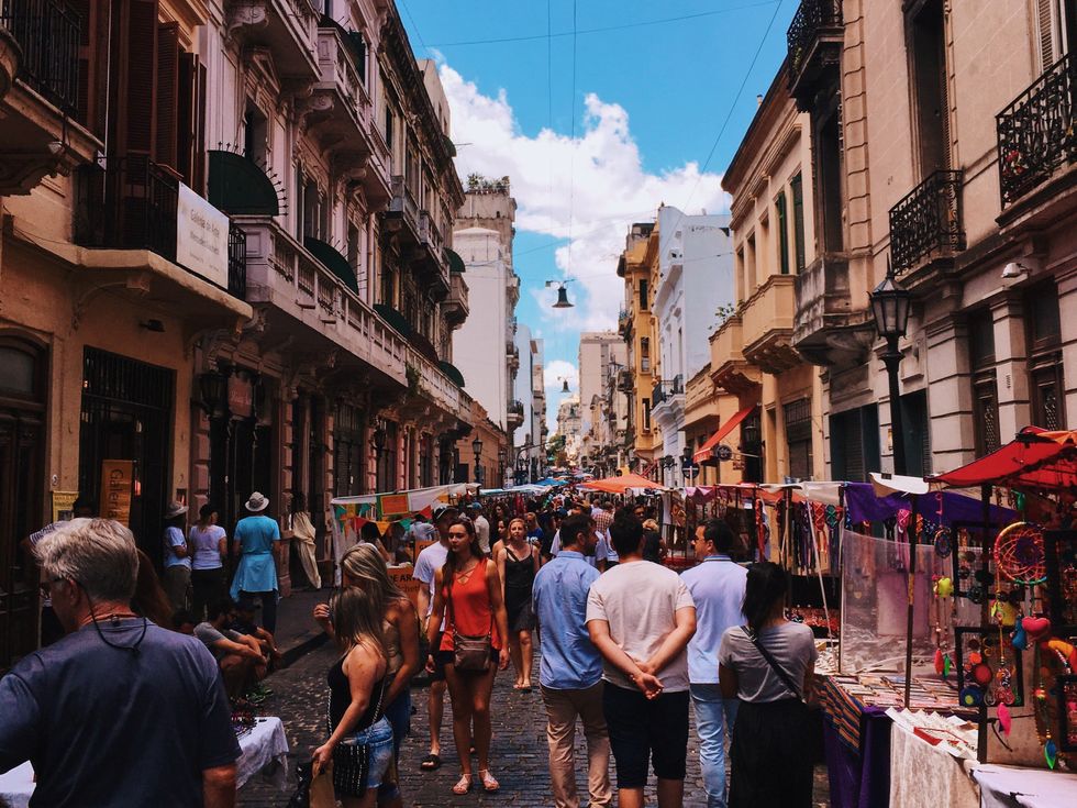 Image of a busy, colorful street market in San Nicolas, CABA, Argentina, filled with people buying things, or just walking.