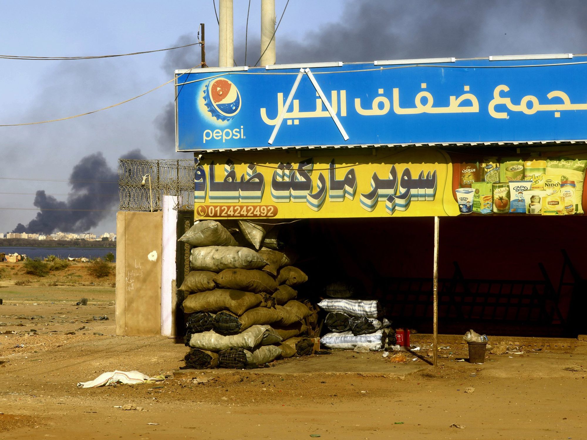 Image of a closed shop with smoke behind it in Khartoum, Sudan.