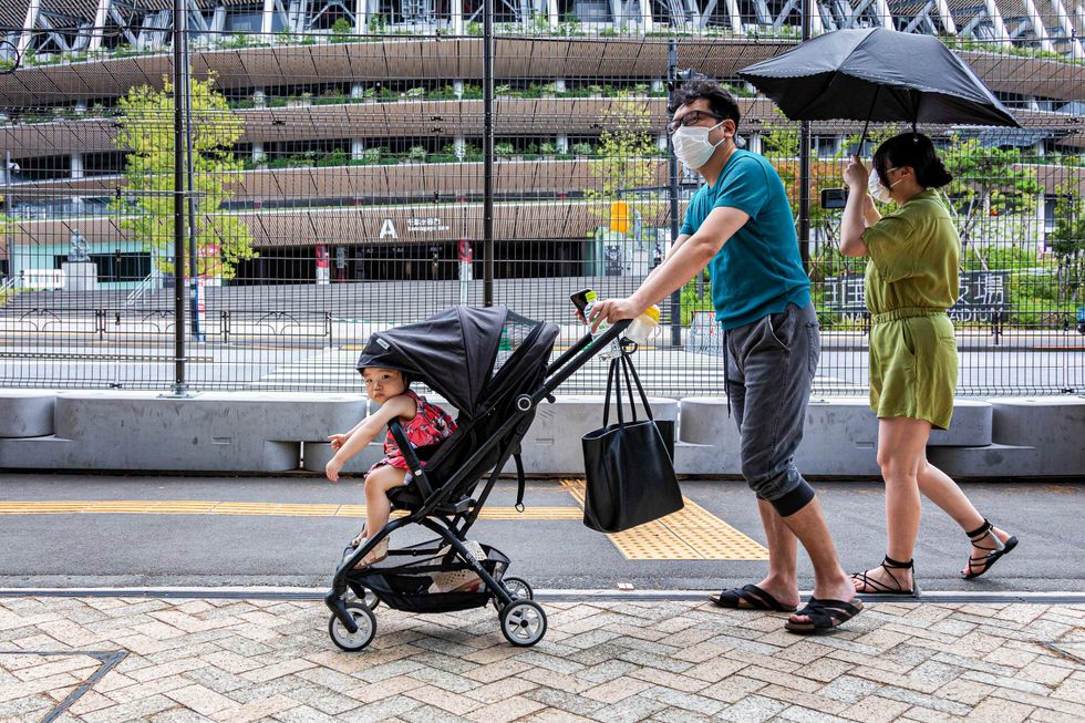 Image of A family passing by the National Olympic Stadium in Tokyo, taking photos and hoping to catch a glimpse of some athletes.