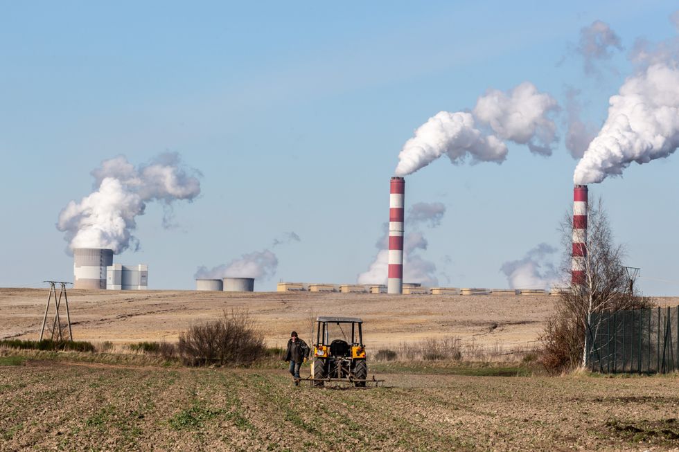 Image of a farmer working on his field in front of PGE Power Station in Belchatow, Poland.