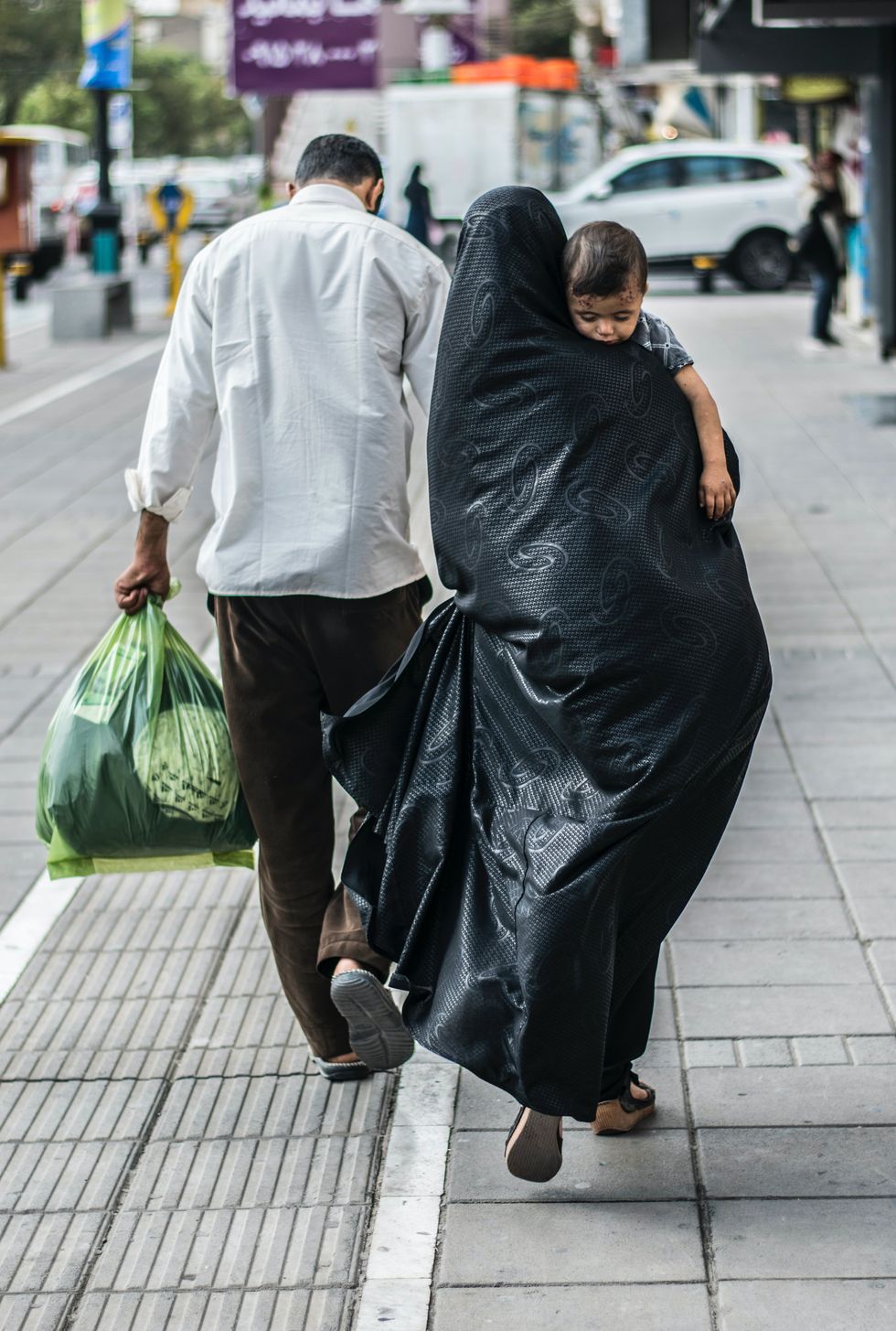 Image of a man and a woman carrying a baby in the streets of Iran.