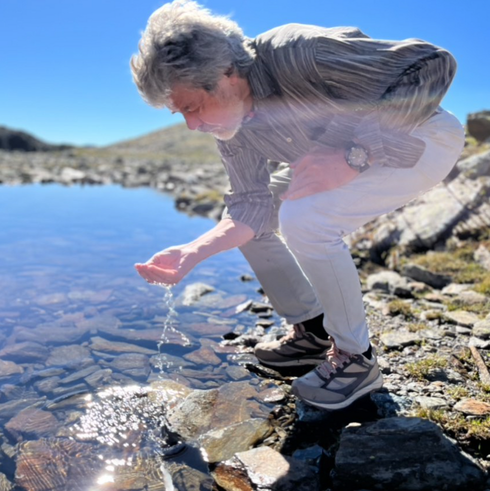 image of a man drinking water from a river.