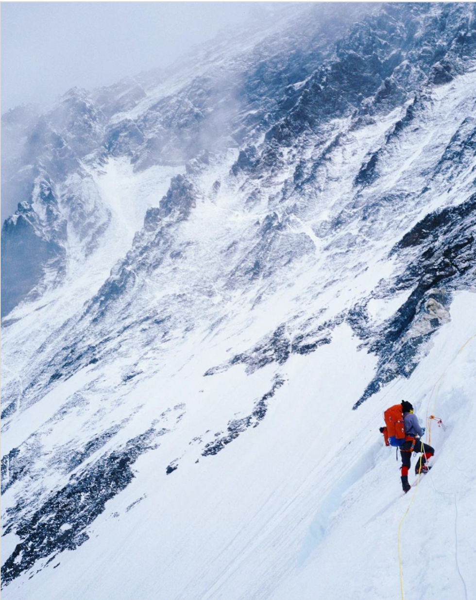 Image of a man in climbing gear climbing a snowy mountain.