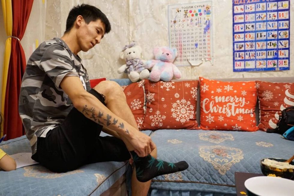 Image of a man putting socks on his feet