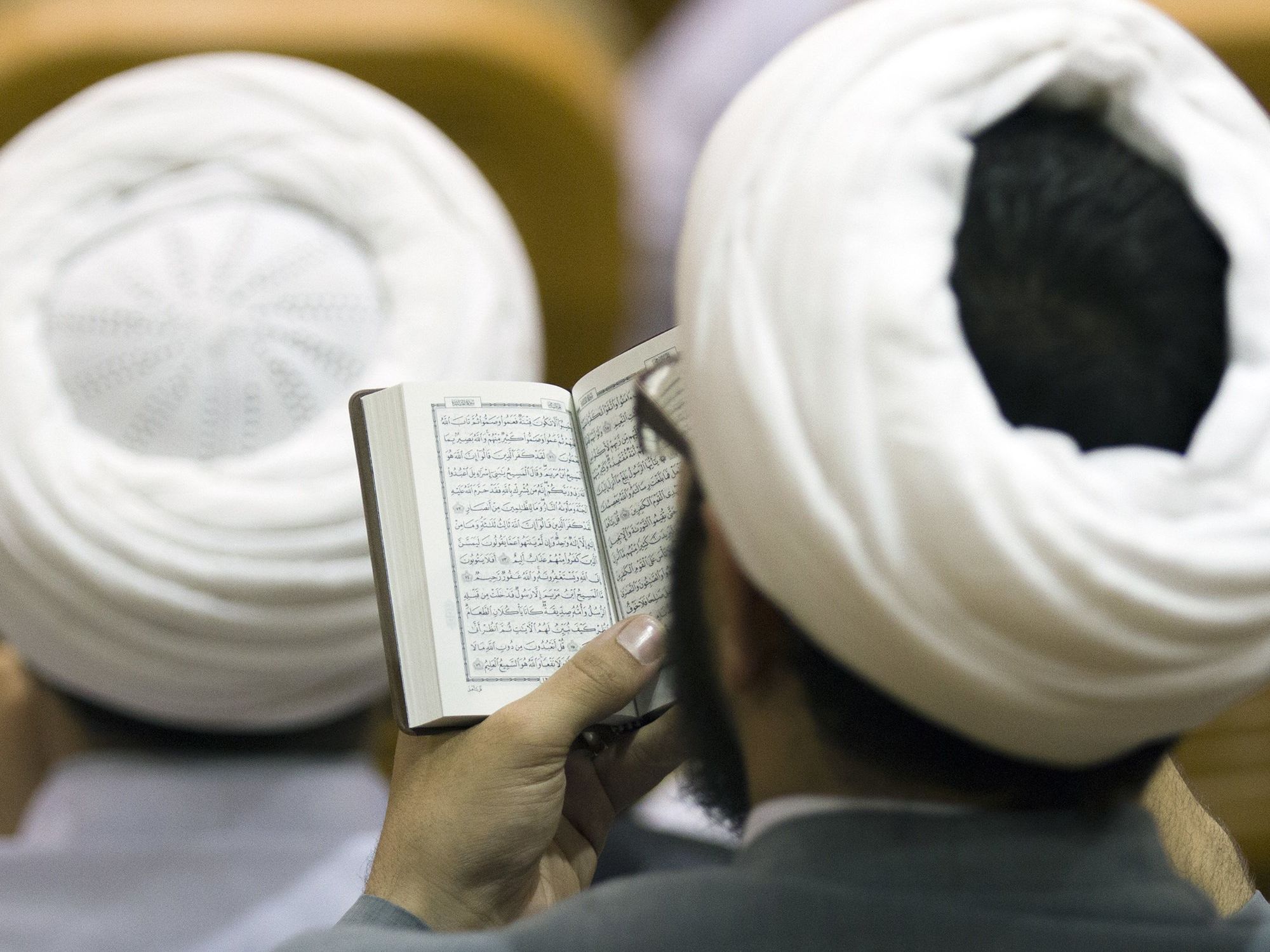 Image of a man reading the Qu'uran after praying