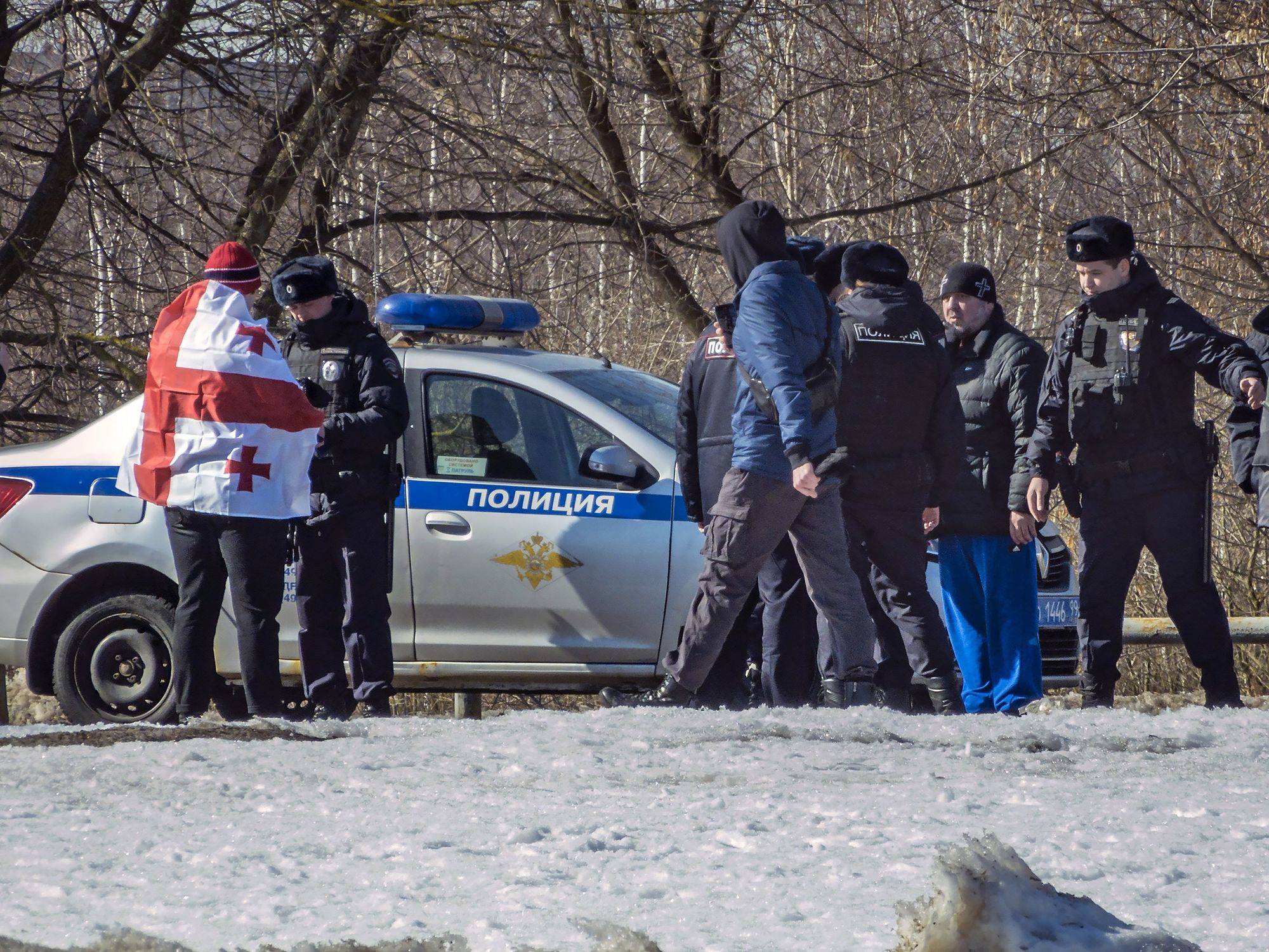 Image of A man wrapped in a Georgian flag is arrested by police in the streets of Moscow.